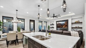 A modern kitchen with a large island, built-in appliances, and pendant lighting. - Oasis at Pecan Valley l Resort Access Included (Hurricane)