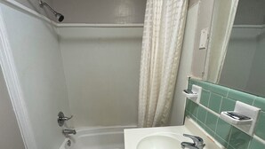 A bathroom with a bathtub, a sink, and a shower curtain. - The Executive Inn (Danville)
