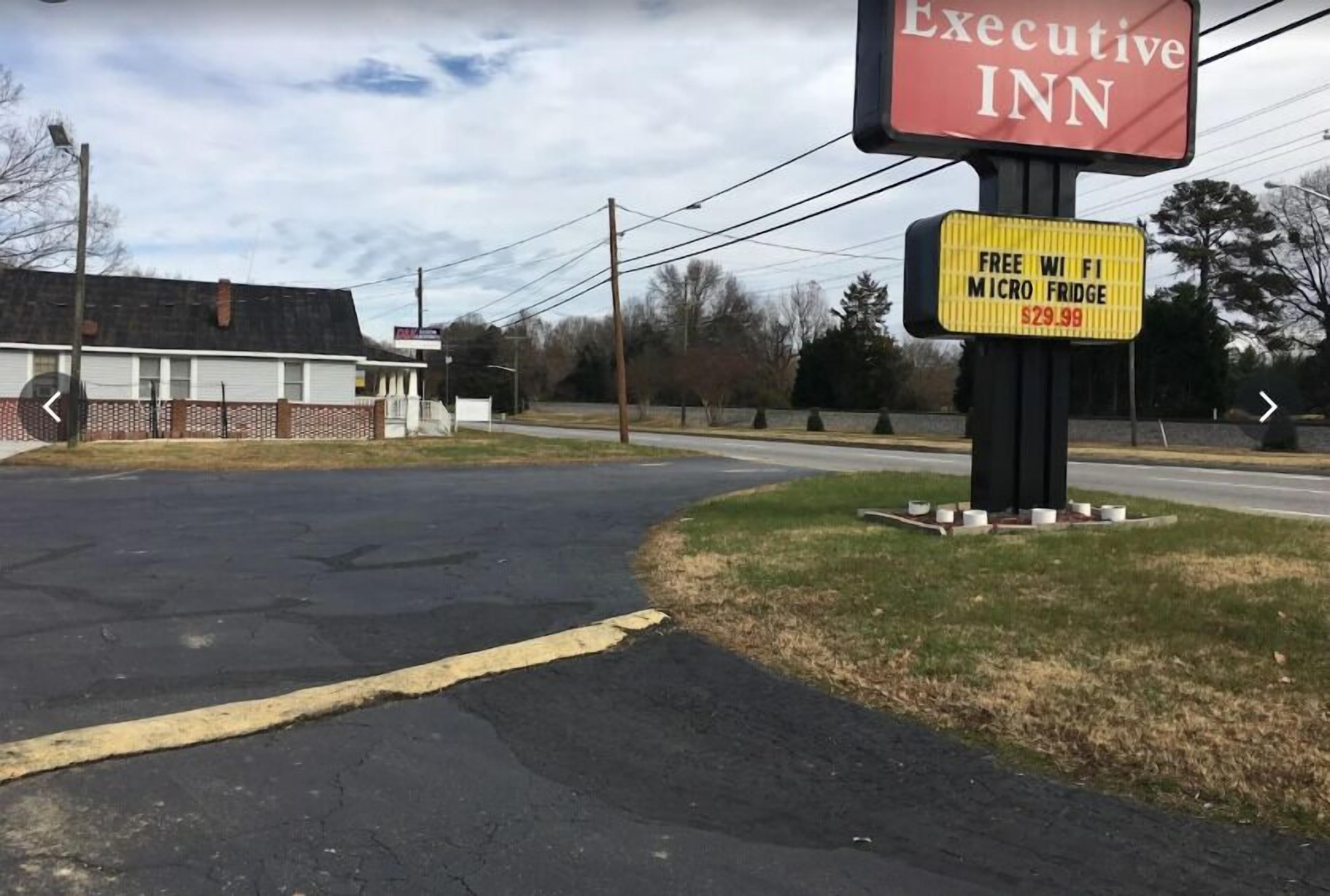 Un estacionamiento con un letrero que anuncia Executive Inn y otro que ofrece WiFi gratis por 29,99 dólares.