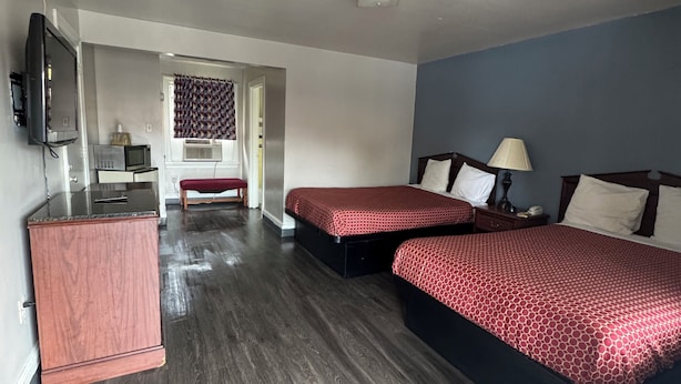 A hotel room with two beds, a TV, a desk, and a trash bin. - The Executive Inn (Danville)