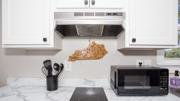 Una cocina con estufa a gas, microondas y un mapa de Kentucky en la pared.