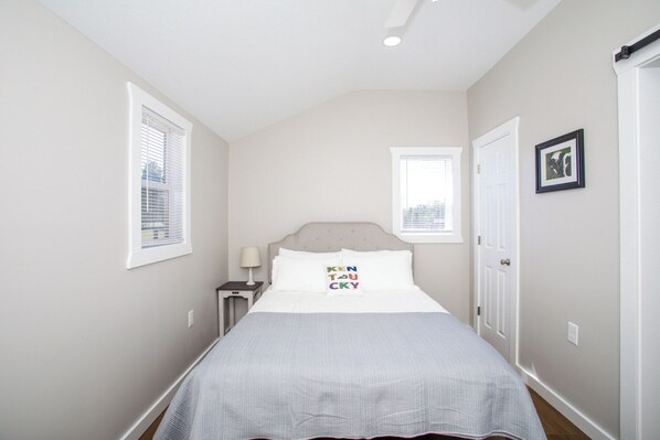 A bedroom with a bed, a nightstand, a window, and a door.