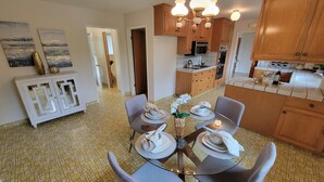 A modern kitchen with wooden cabinets, a dining area with a round table set for four, and a tiled floor. - Spacious 4-bedroom house in Los Altos (Los Altos)