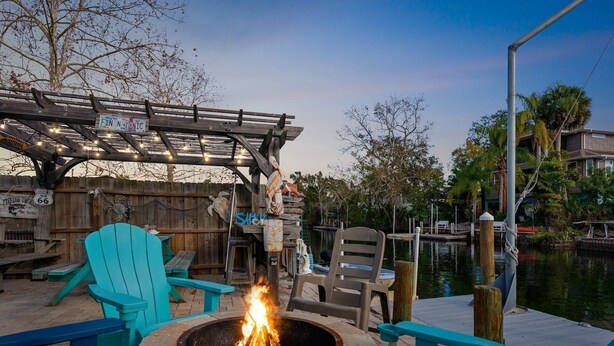 An outdoor seating area with a fire pit, wooden deck, and chairs.