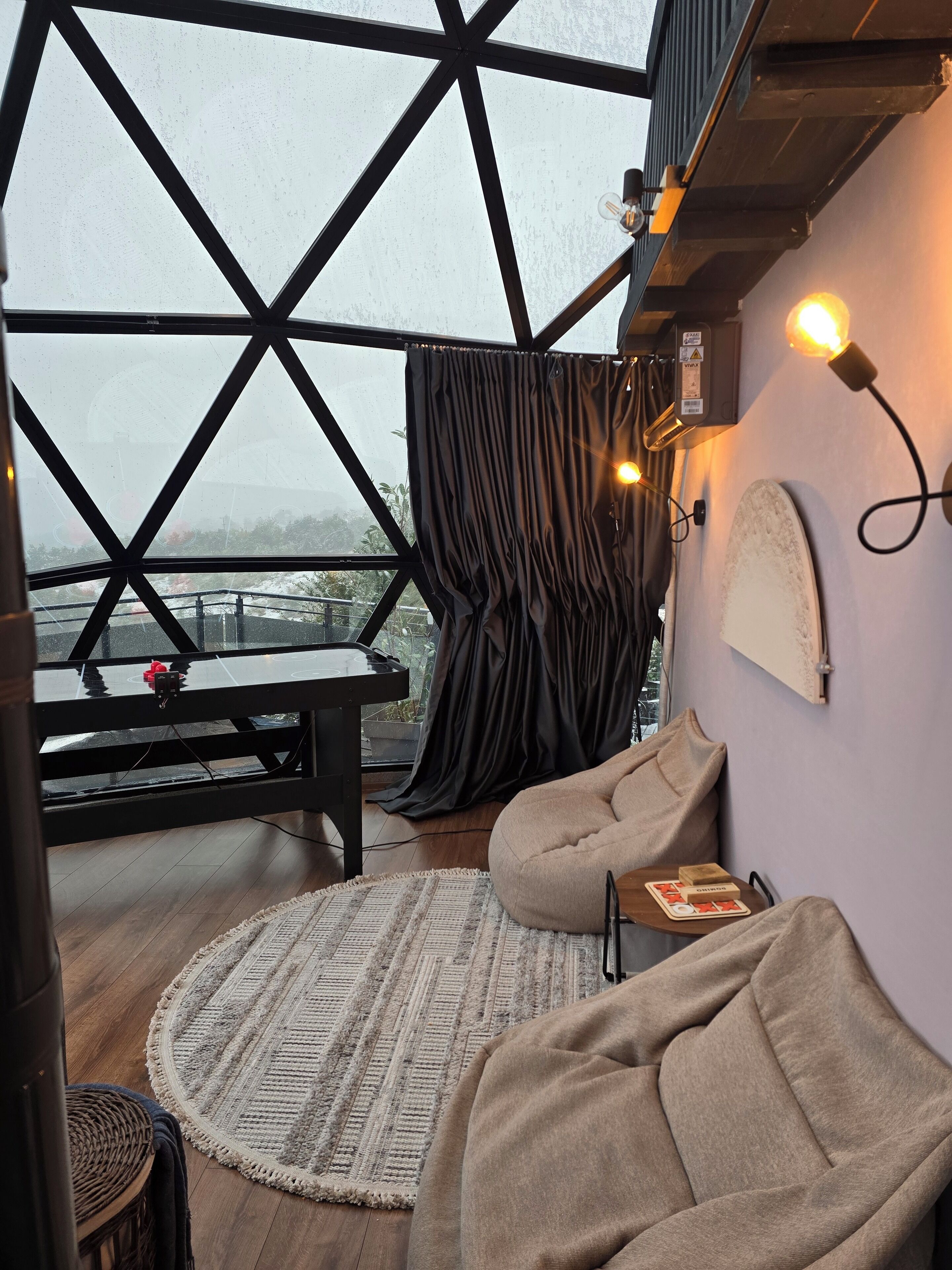 A cozy room with a piano, a round rug, and a view through large windows.