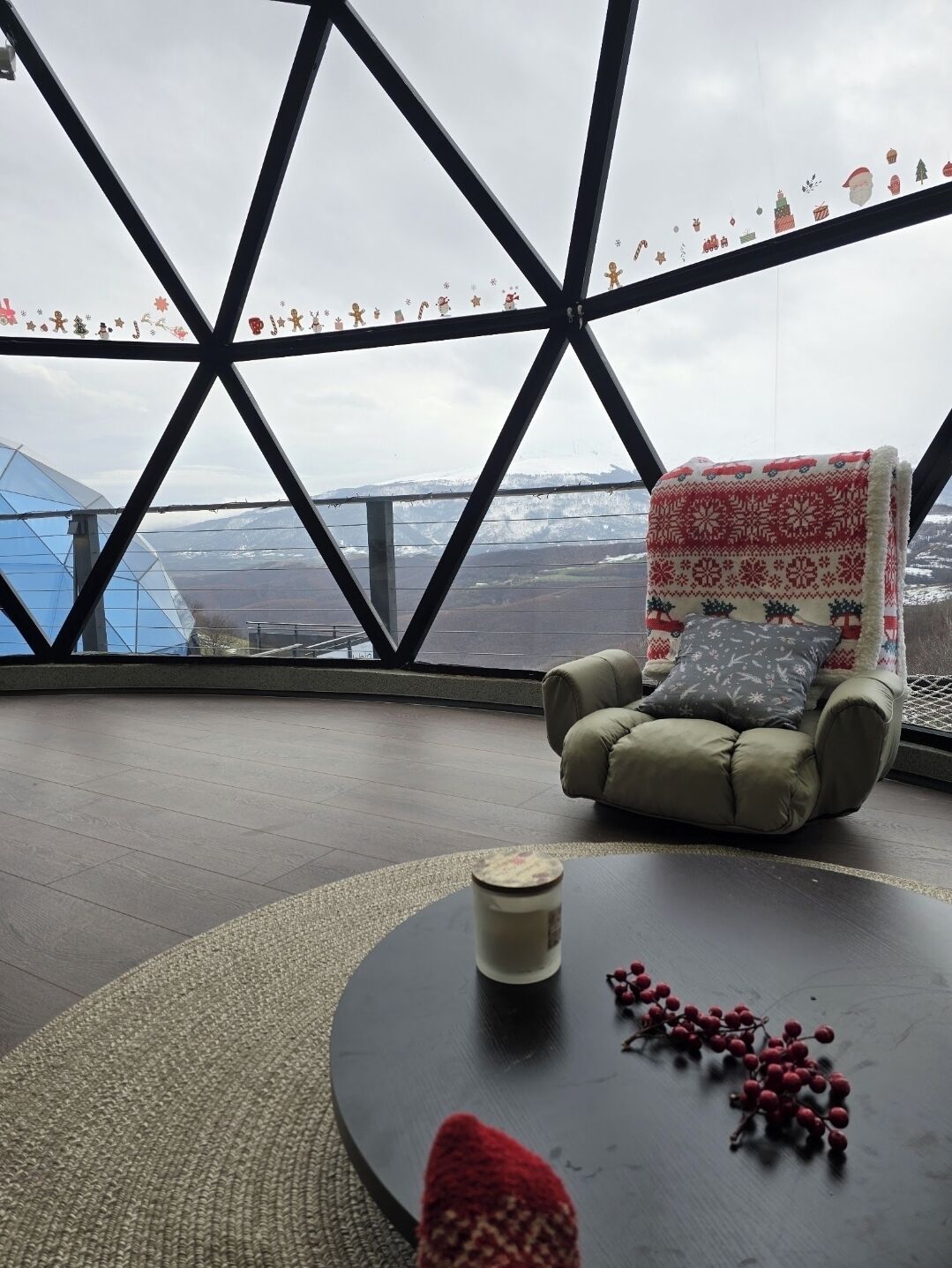 A cozy seating area with a view of a snowy landscape through a geometric window structure.