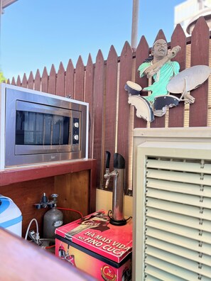 A kitchen area with a microwave, a coffee machine, and a wooden cabinet.