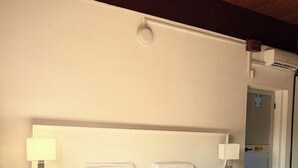 A bedroom with a bed, two bedside tables, a nightstand, a lamp, a rug, and a ceiling light. - Cozy Modern Studio in Maculusso, Luanda – Central & Secure Location (Luanda)