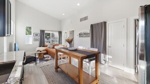 A modern living room with a wooden dining table, a sofa, and a large window. - Cozy 2bd Close to Downtown Driggs (walkable) (Driggs)