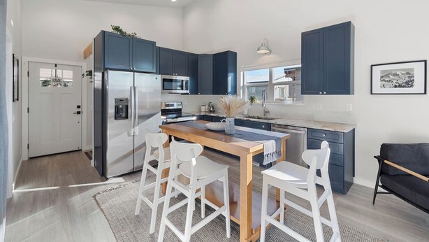 A modern kitchen with dark blue cabinets, stainless steel appliances, and a wooden dining table with white chairs. - Cozy 2bd Close to Downtown Driggs (walkable) (Driggs)