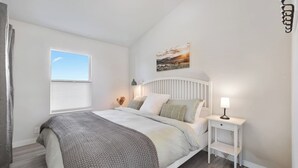 A bedroom with a bed, bedside table, lamp, and a window with blinds. - Cozy 2bd Close to Downtown Driggs (walkable) (Driggs)