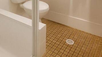 A bathroom with a toilet, a glass shower enclosure, and a towel rack with towels.