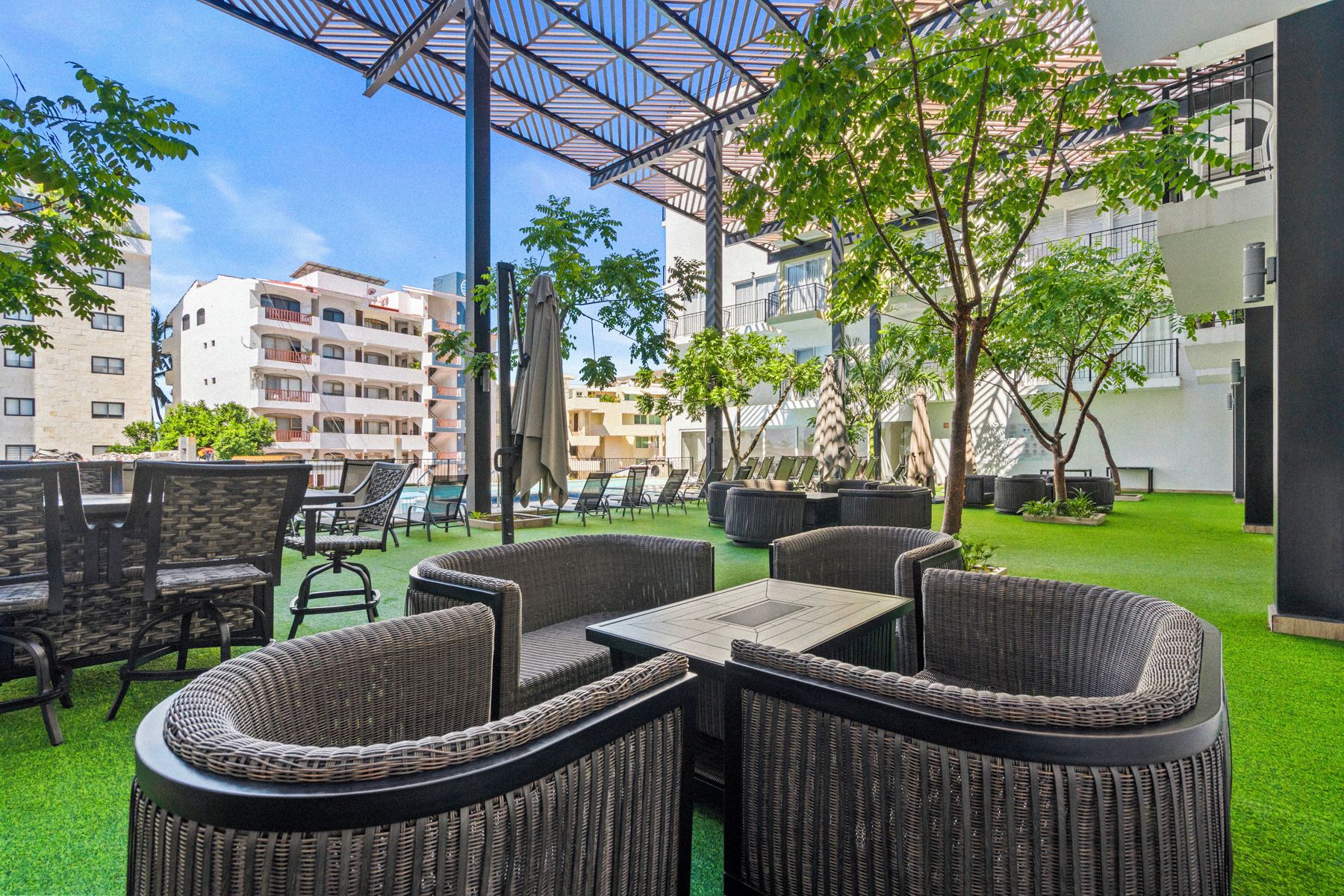 An outdoor seating area with wicker furniture and a pool in the background.