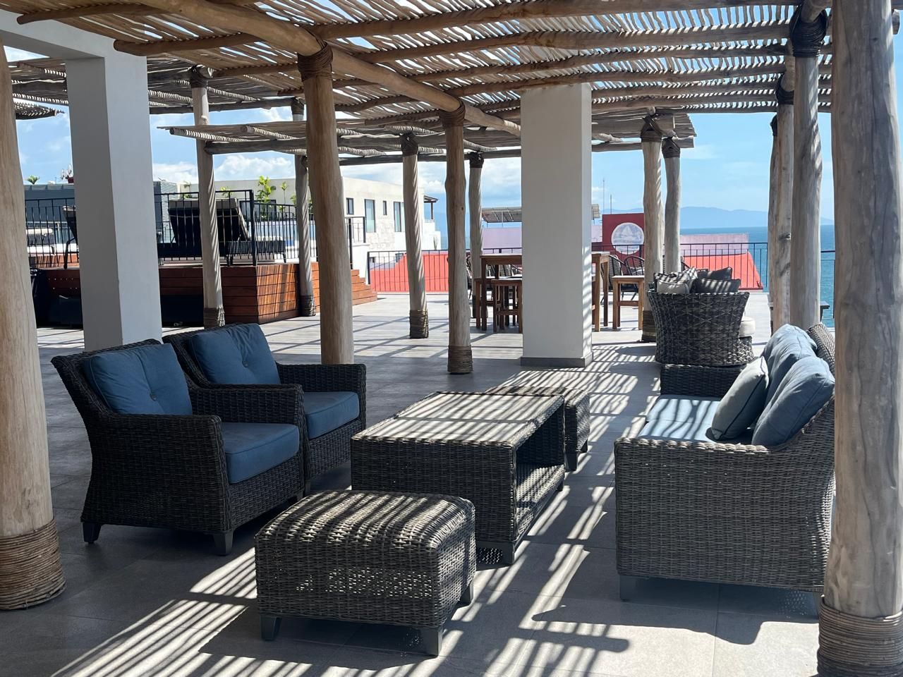 Un espacio de estar al aire libre con mobiliario de mimbre y una estructura de pérgola.