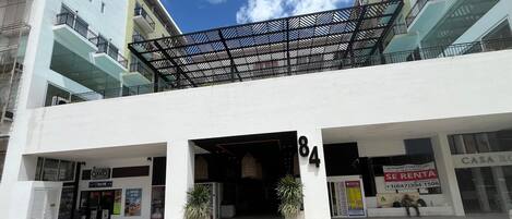 A modern building with a covered entrance, numbered 84, featuring a commercial space on the ground floor and residential units above.
