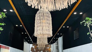 A modern interior with a central walkway, decorative macramé chandeliers, and potted plants. - Life Bucerias Modern Studio Near Beach (Bucerías)