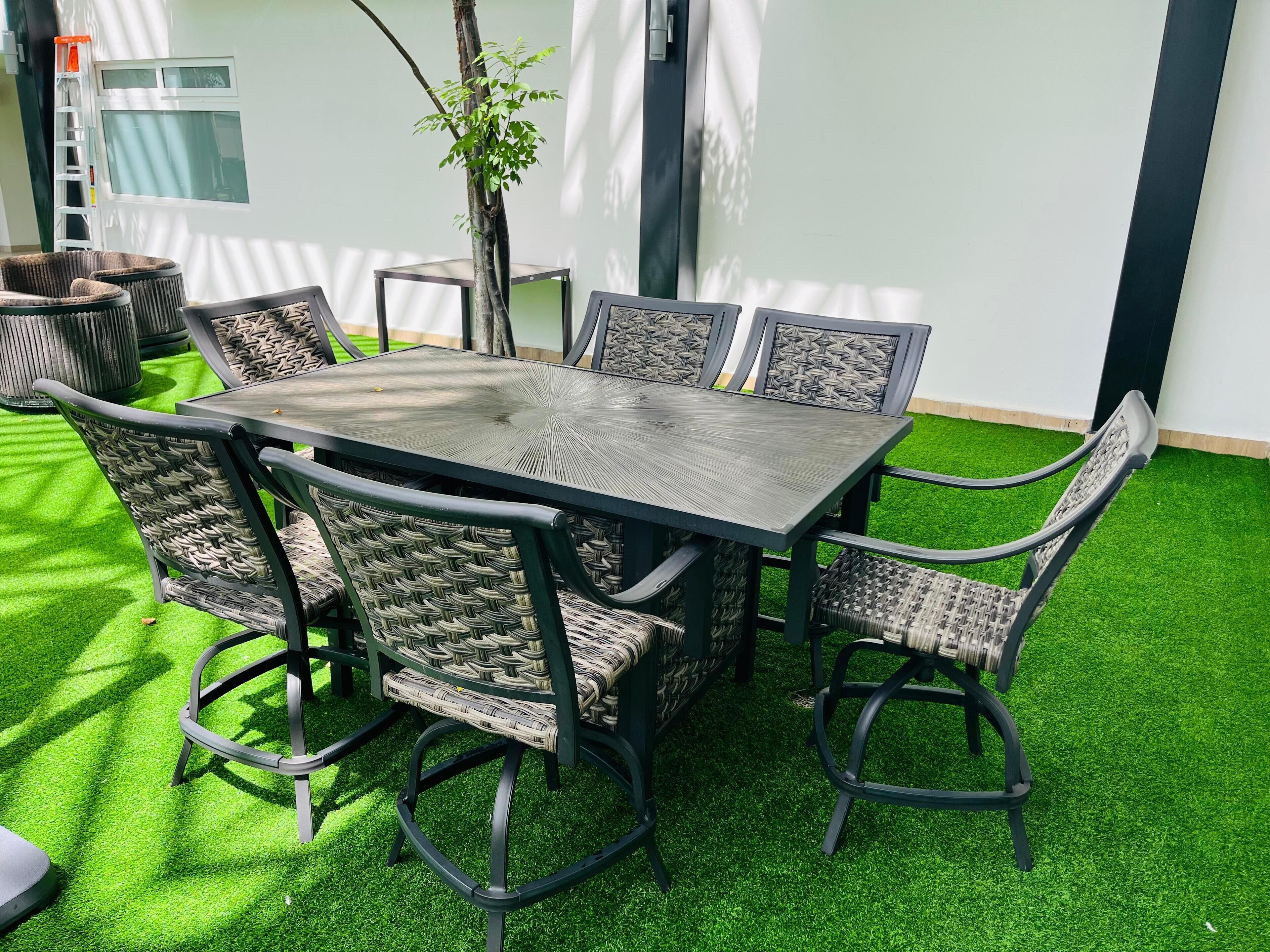 An outdoor patio with a rectangular table and six wicker chairs.