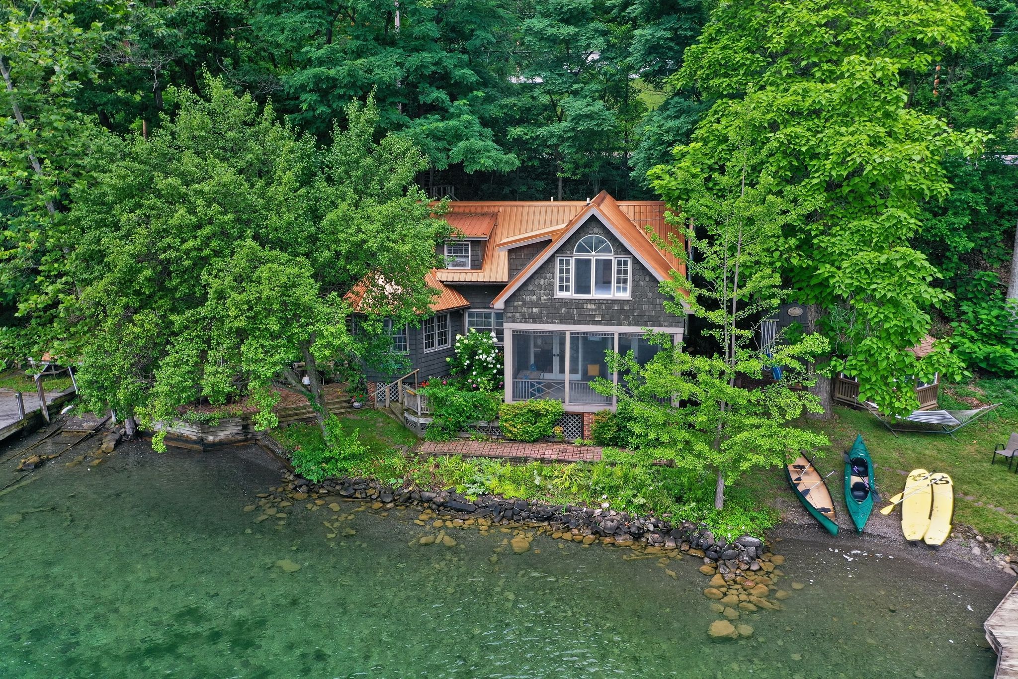 Ein Haus mit großer Veranda, einem Steg und Kajaks.