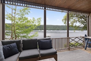 A covered outdoor seating area with a view of a lake and forest. - Keukamonga, A Lakefront Gem with Panoramic Views (Hammondsport)