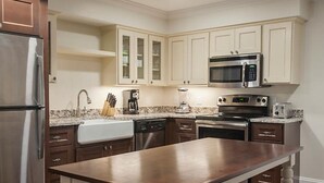 A kitchen with a central island, stainless steel appliances, and white cabinetry.