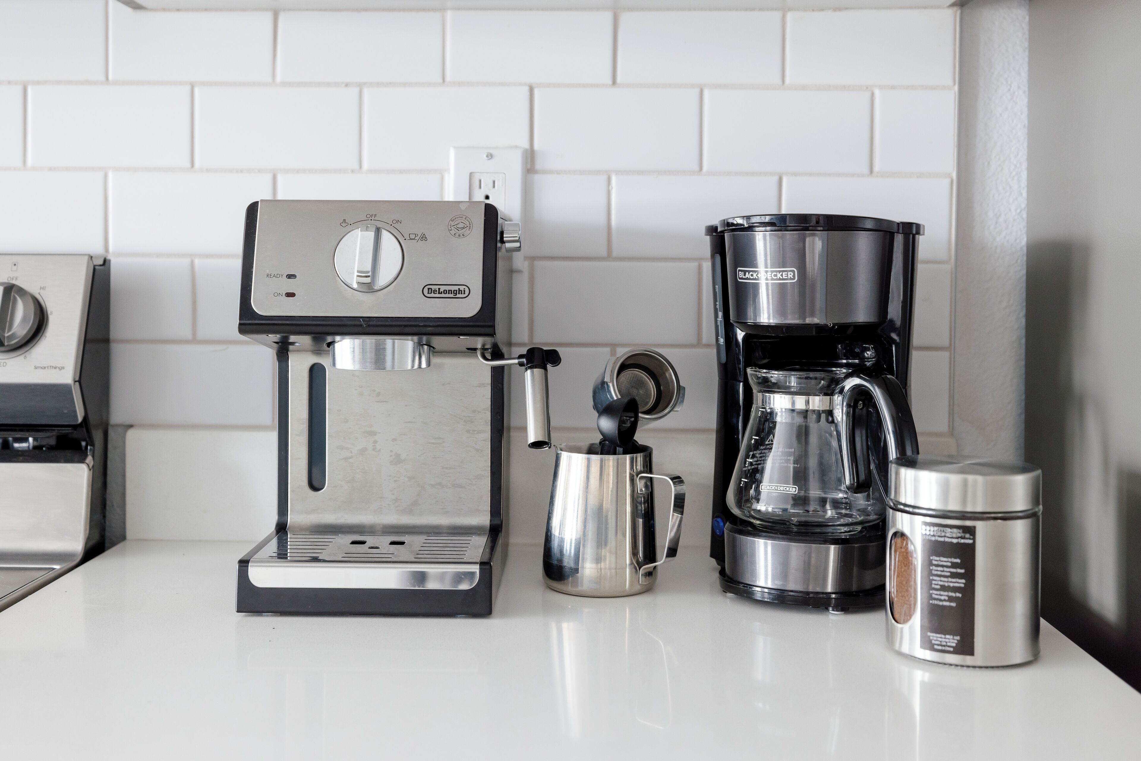 A coffee maker, a coffee pot, and a coffee container on a kitchen counter.