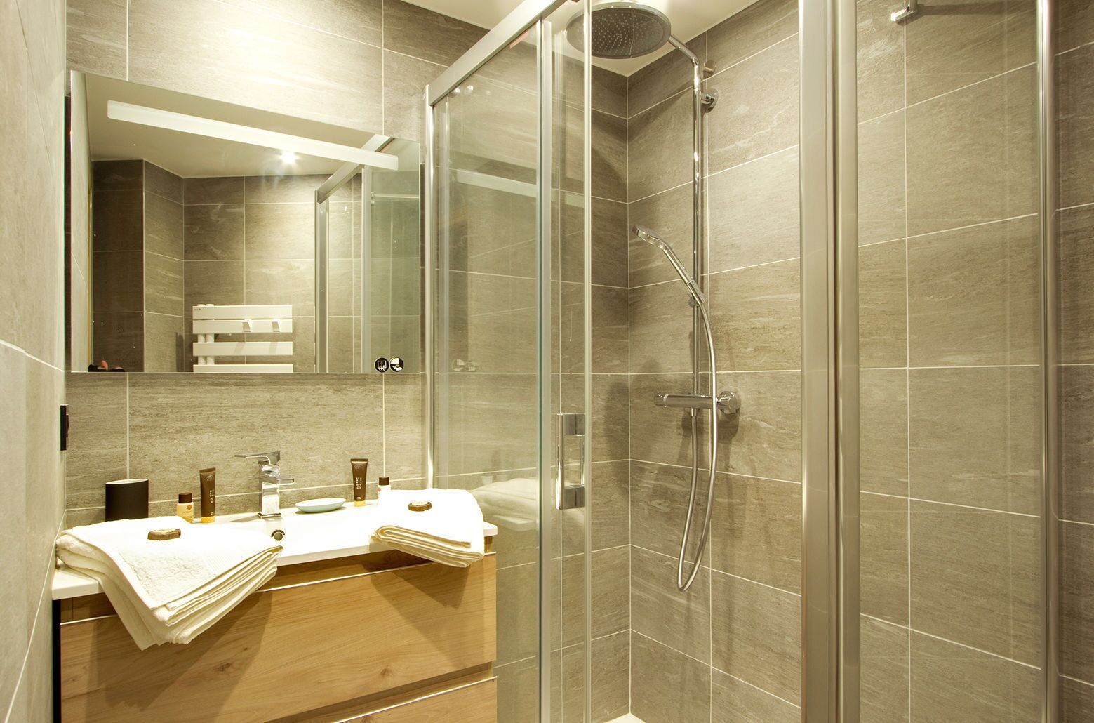 A modern bathroom with a glass shower enclosure, a vanity with a mirror, and a towel rack.