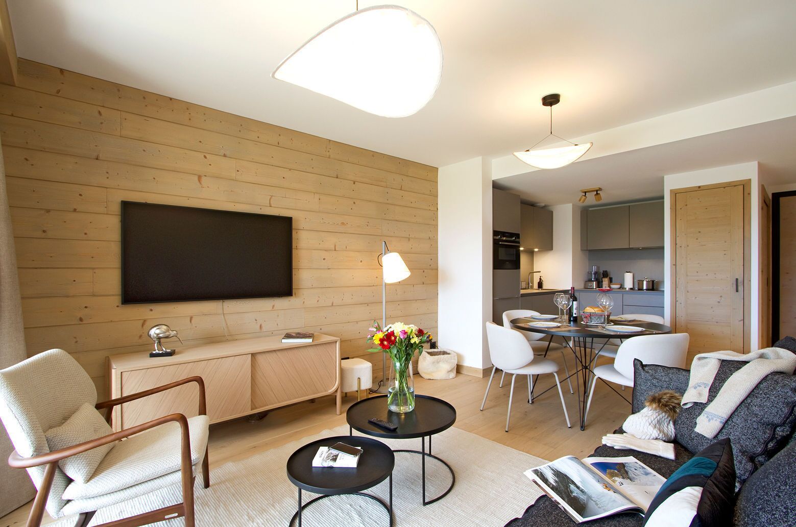 Un soggiorno moderno con una TV a schermo piatto, un'area pranzo e una cucina sullo sfondo.