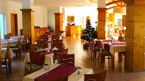 A dining area with tables and chairs, a Christmas tree, and a kitchen in the background. - Cvl Club House (Lagos)