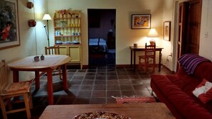 A cozy living room with a red sofa, a dining table with chairs, a kitchen area with shelves, and a hallway leading to another room. - Amazing Oasis 2-bedroom apartment in Centro Oaxaca de Juárez (Oaxaca de Juárez)