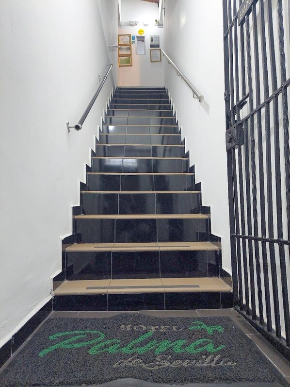 A staircase with black steps and a metal railing, leading to a door with a sign that reads "EMPORIO". - Hotel Palma Sevilla Medellin (Medellín)