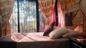 A bed with a white mattress and two pillows, a nightstand, and a window with curtains. - Hotel Palma Sevilla Medellin (Medellín)