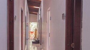 A hallway with wooden beams on the ceiling, white walls, and doors on both sides. - Hotel Palma Sevilla Medellin (Medellín)