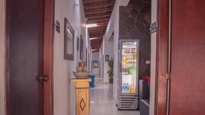 A hallway with wooden doors, a refrigerator, and a small table with items on it. - Hotel Palma Sevilla Medellin (Medellín)