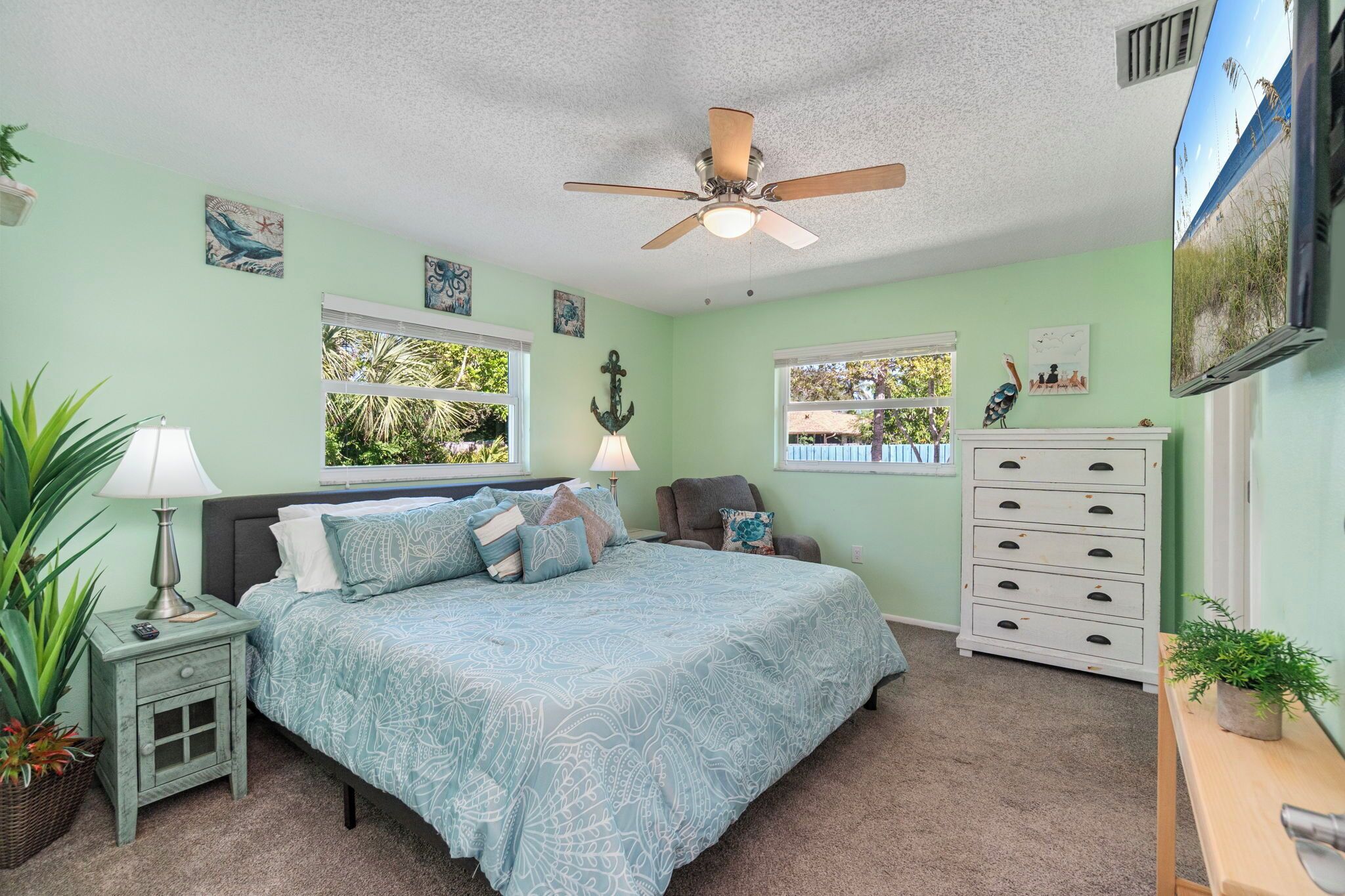 A bedroom with a bed, nightstand, dresser, and ceiling fan.