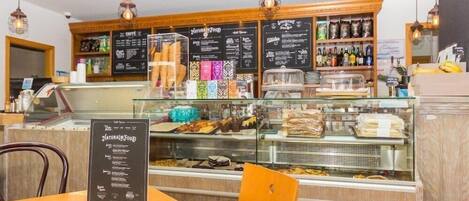 A cafe with a menu board, display cases with pastries, and a counter with beverages.