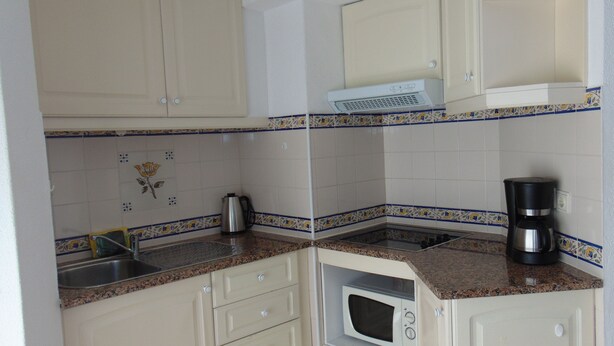 A compact kitchen with white cabinets, a microwave, a coffee maker, and a kettle on the countertop. - Senhora Da Rocha (Lagoa)