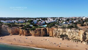 A coastal town with a beach, rocky cliffs, and white buildings. - Senhora Da Rocha (Lagoa)