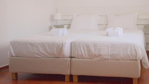 A double bed with white linens, a bedside table with a lamp, and two framed pictures on the wall. - Senhora Da Rocha (Lagoa)