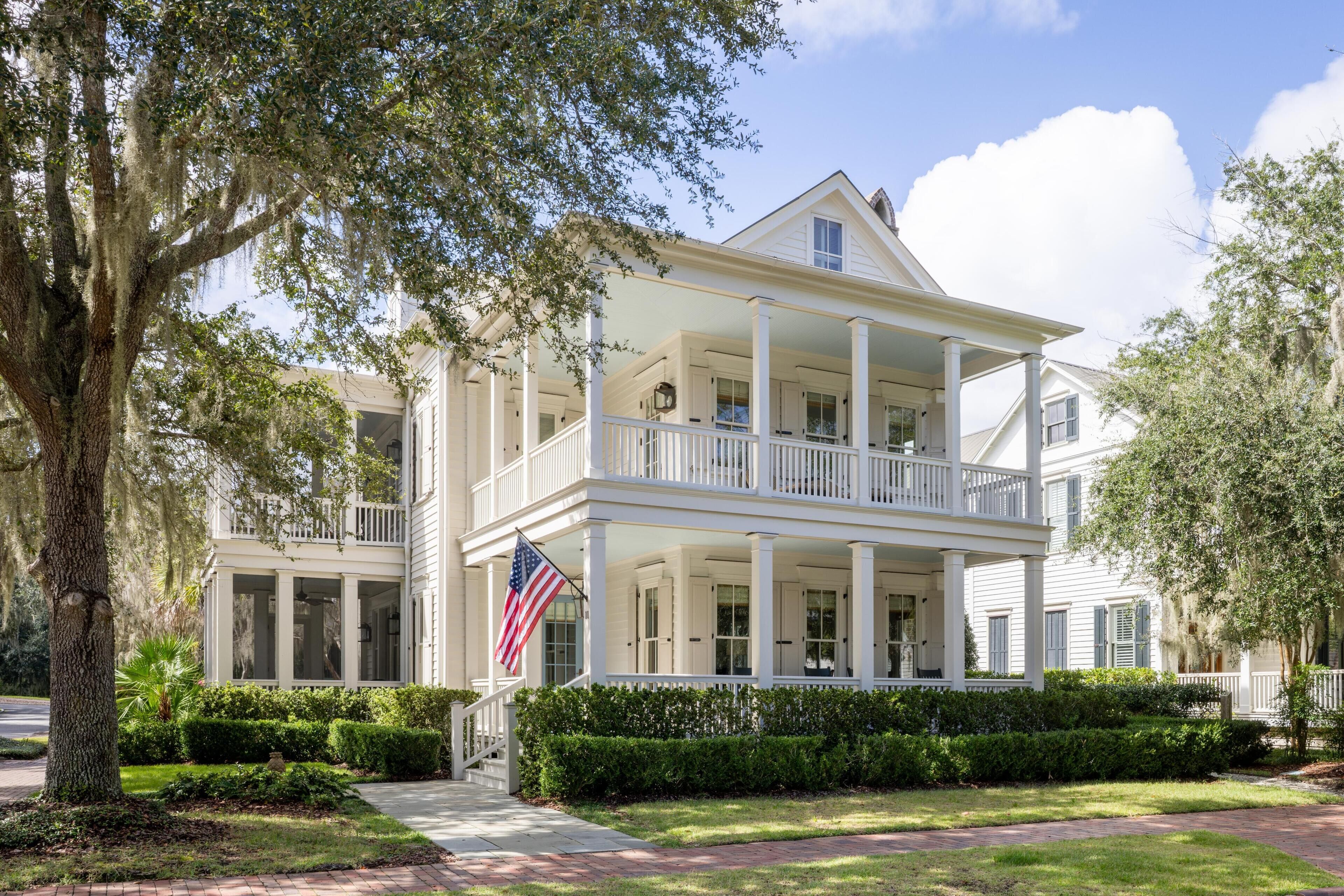 A two-story white house with a porch, columns, and an American flag.