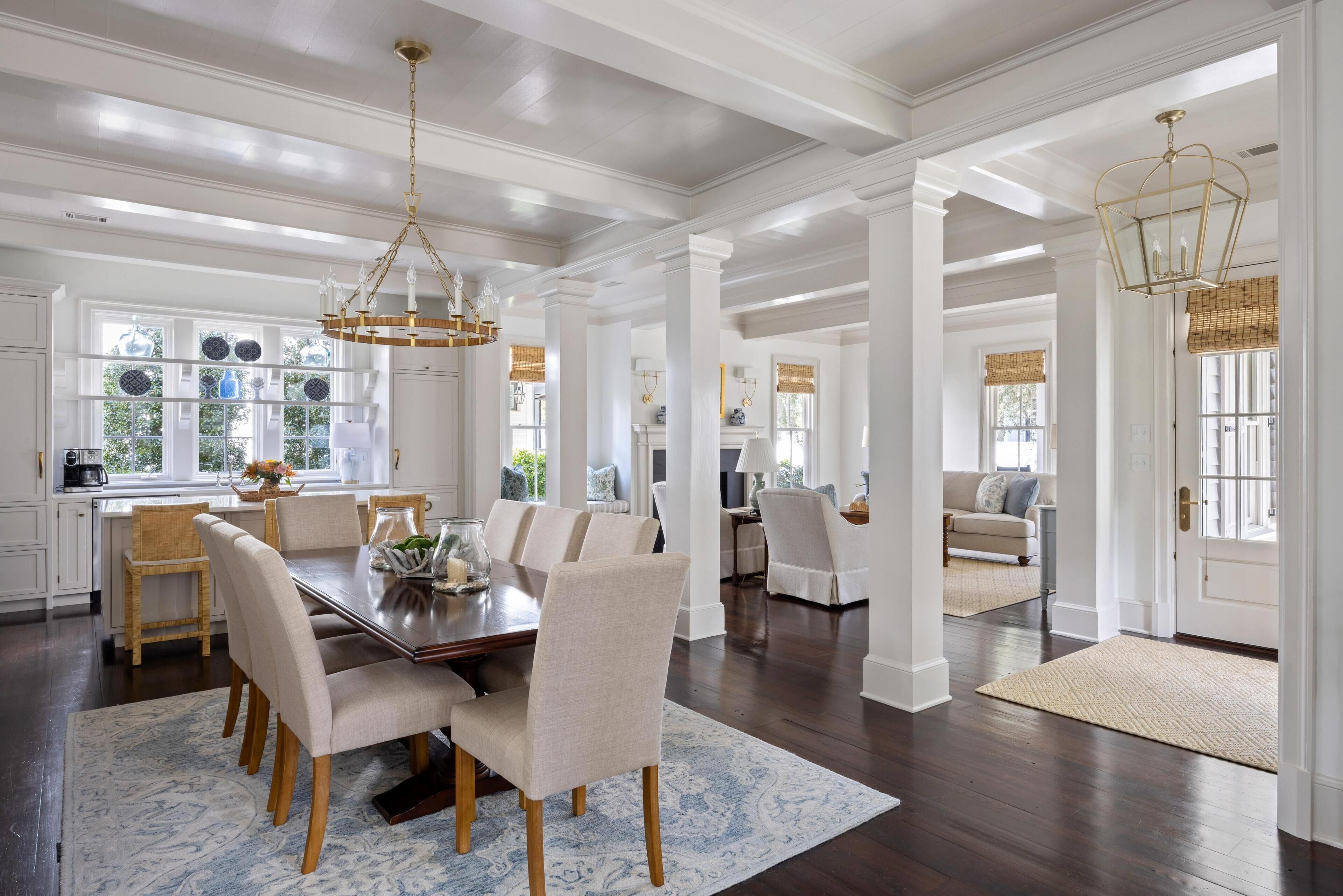 A spacious dining area with a large wooden table, multiple chairs, and a chandelier.