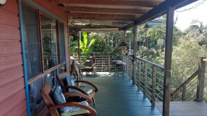 Eine Holzterrasse mit Stühlen und einem Tisch, mit Blick auf einen üppigen Garten.