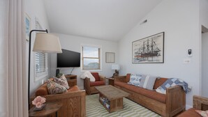 Una sala de estar acogedora con muebles de madera, un televisor de pantalla plana y un cuadro de un barco en la pared.