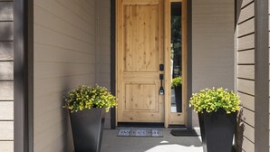 A wooden double door with a mailbox and a welcome mat.
