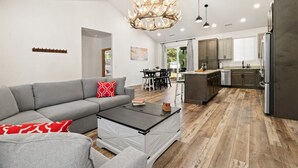 A modern living room with a grey sofa, a coffee table, and a chandelier.