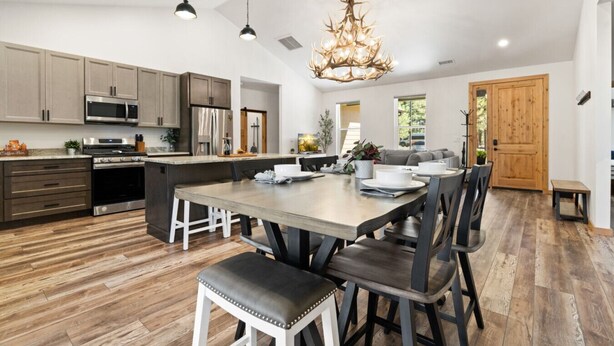 A modern kitchen with a central island, stainless steel appliances, and a dining area with a wooden table and chairs.