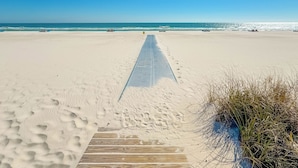 Une plage de sable avec une promenade en bois qui mène à l’océan.