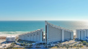 Un hôtel situé en bord de mer, composé de plusieurs étages, avec une tour centrale et offrant une vue sur la plage.