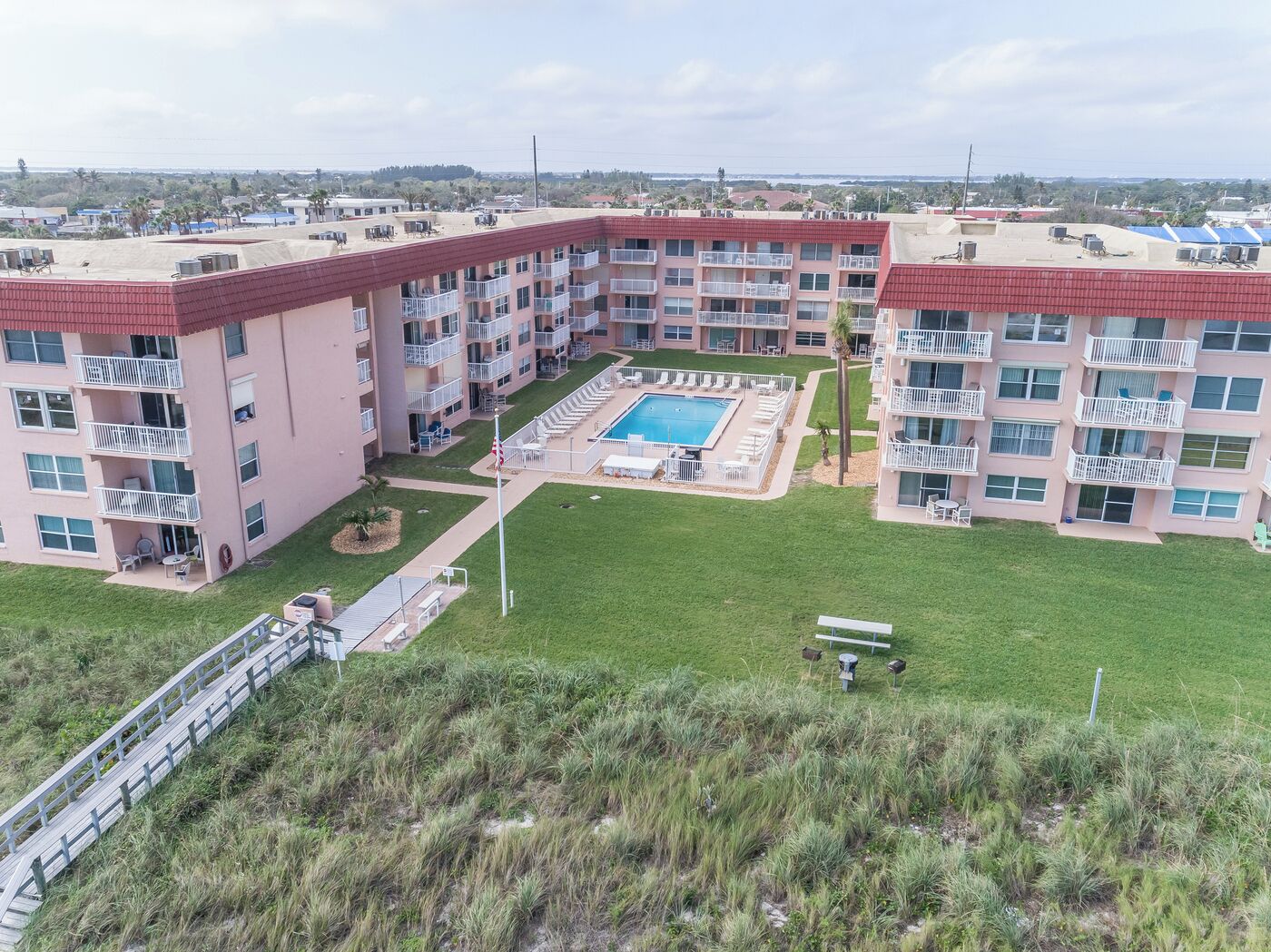 Un immeuble résidentiel à plusieurs étages doté d’une piscine centrale, de balcons et d’une cour verdoyante.