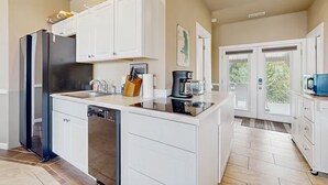 Eine moderne Küche mit weißen Schränken, einem schwarzen Kühlschrank und einem Geschirrspüler.