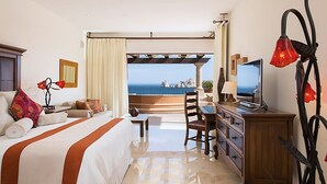 Une chambre d’hôtel avec un lit, un bureau, une télévision et une vue sur l’océan.